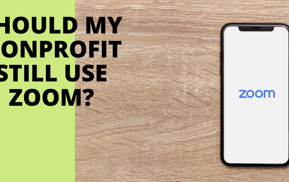 Header image for Should My Nonprofit Still Use Zoom blog post. Phone laying on wood surface with Zoom logo on screen