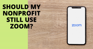 Header image for Should My Nonprofit Still Use Zoom blog post. Phone laying on wood surface with Zoom logo on screen