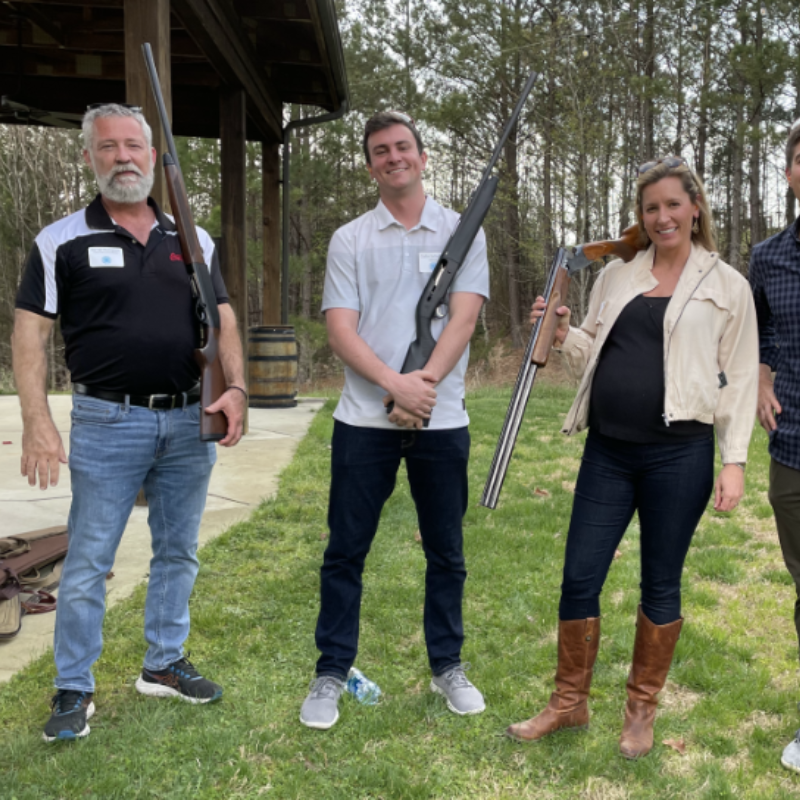 Technology leaders posing with gun at clay shoot competition