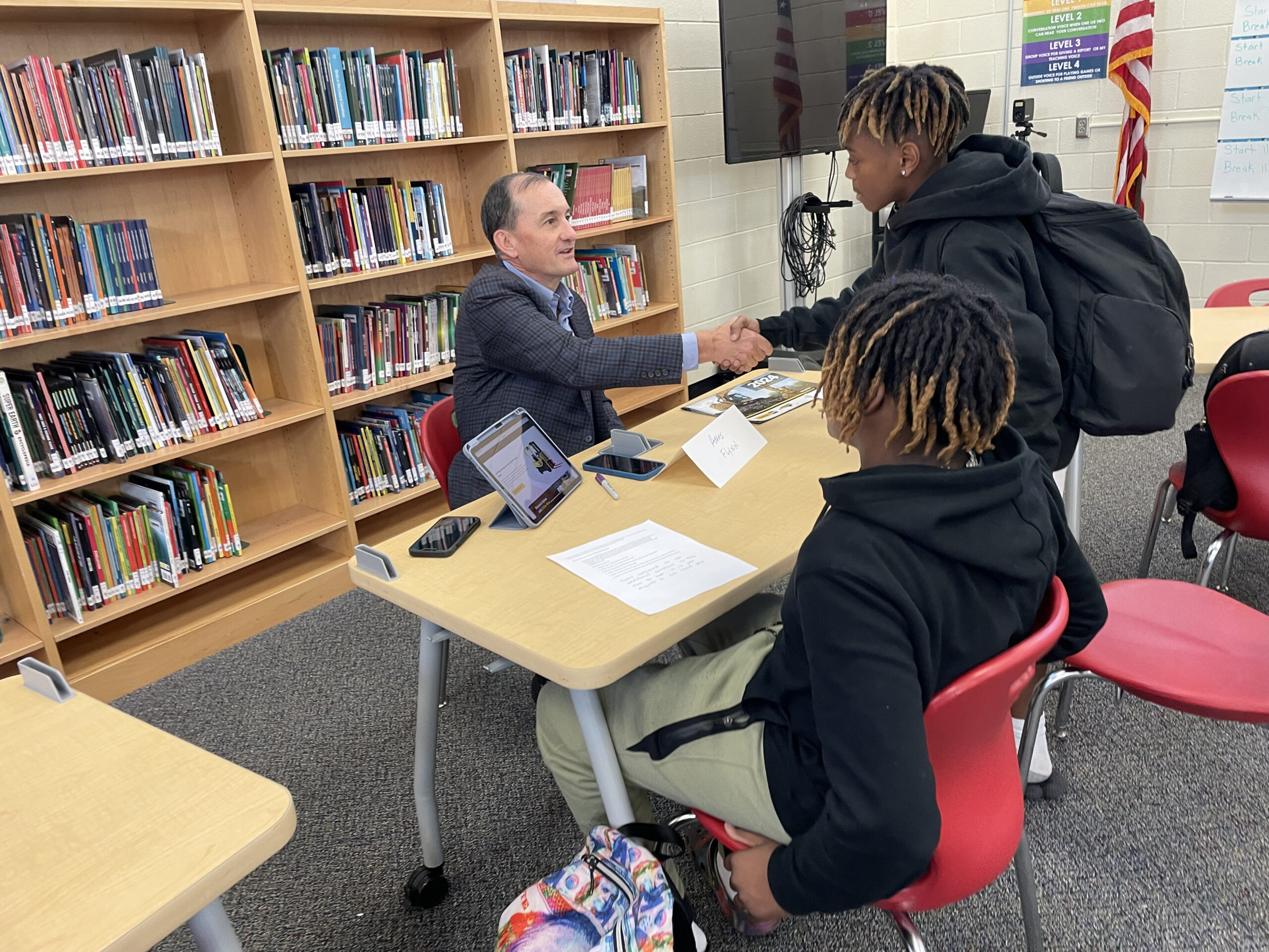 Apparo CXO Tech Council Member and Chief Information Officer at Weisiger Group, Ames Flynn, shakes the hand of eighth grade students eager to learn.